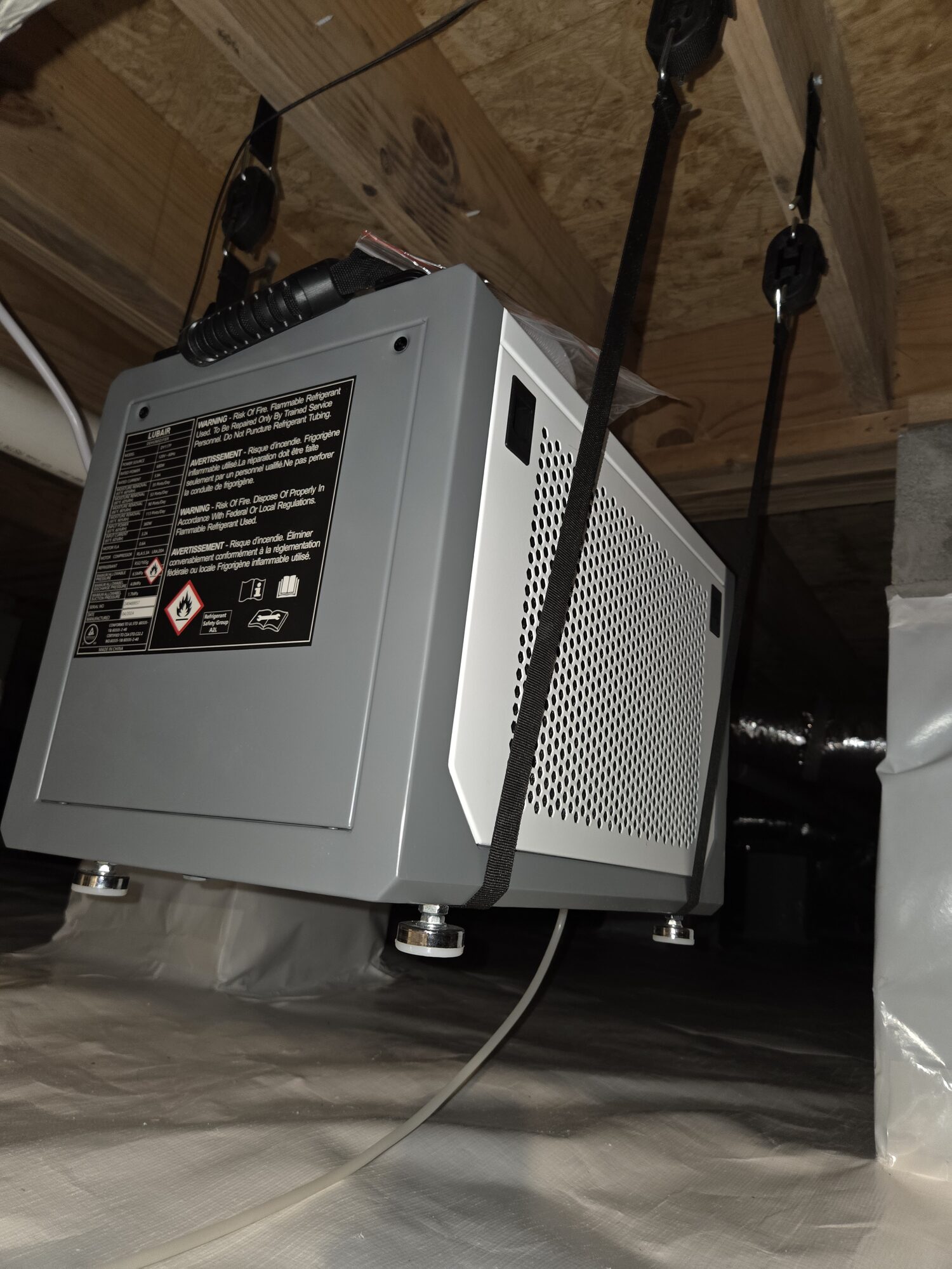 Crawlspace dehumidifier hung from the floor joists in a finished, encapsulated crawlspace
